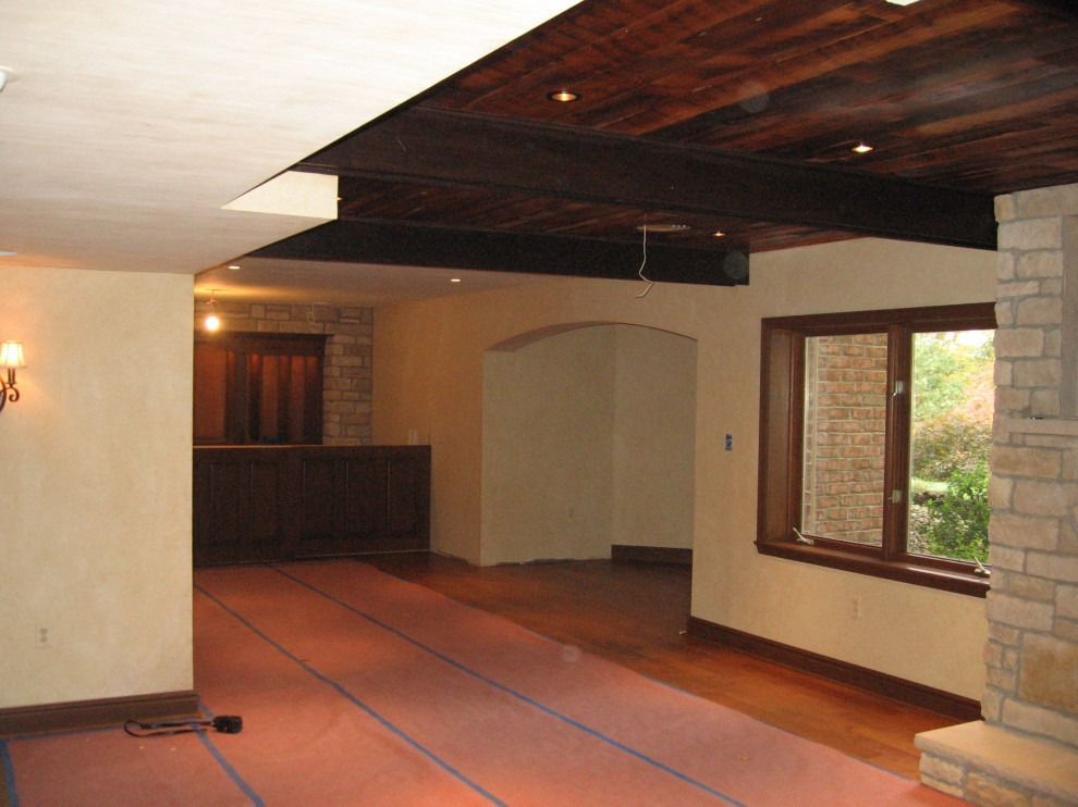 An empty room with a brick fireplace and a wooden ceiling.