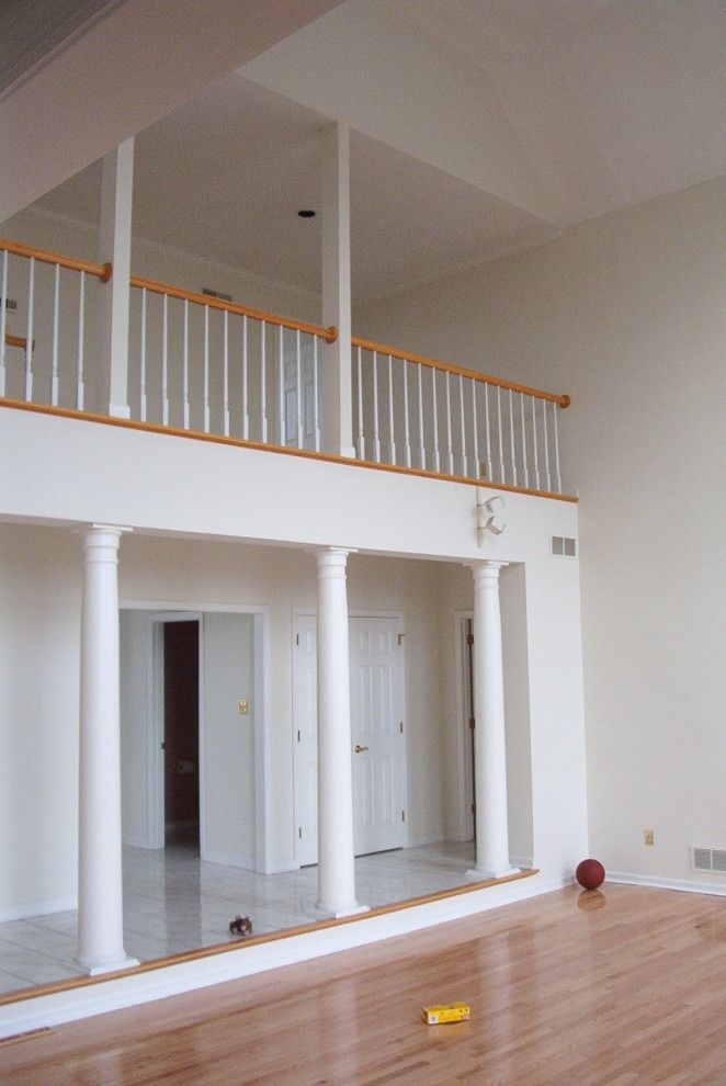 A large empty room with columns and a balcony.