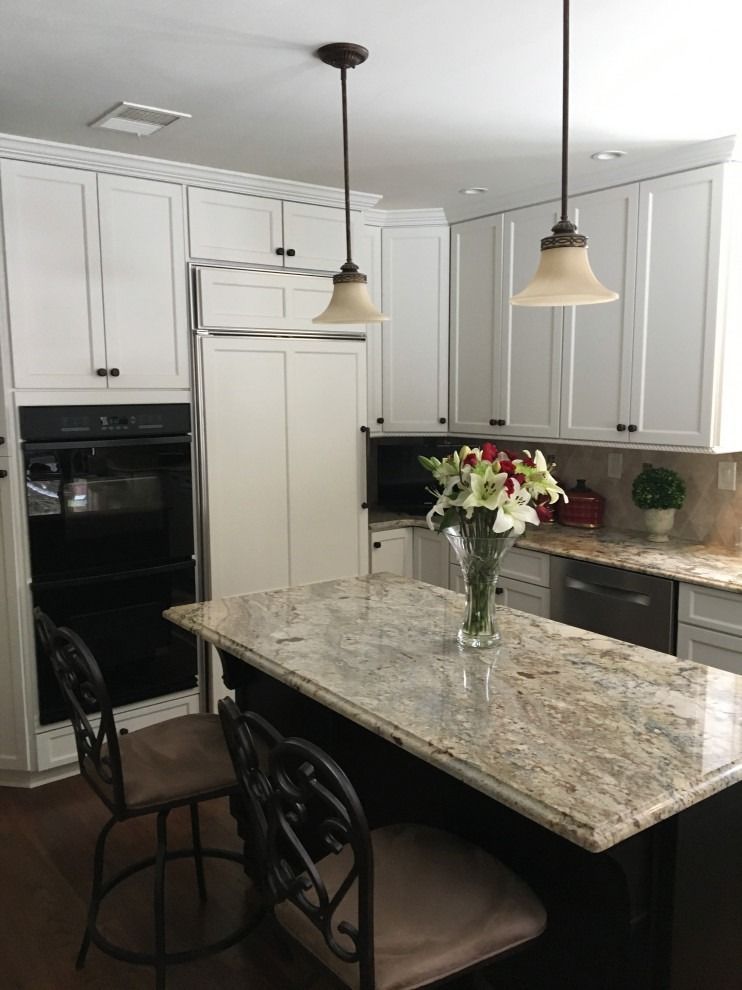 A kitchen with white cabinets and granite counter tops.