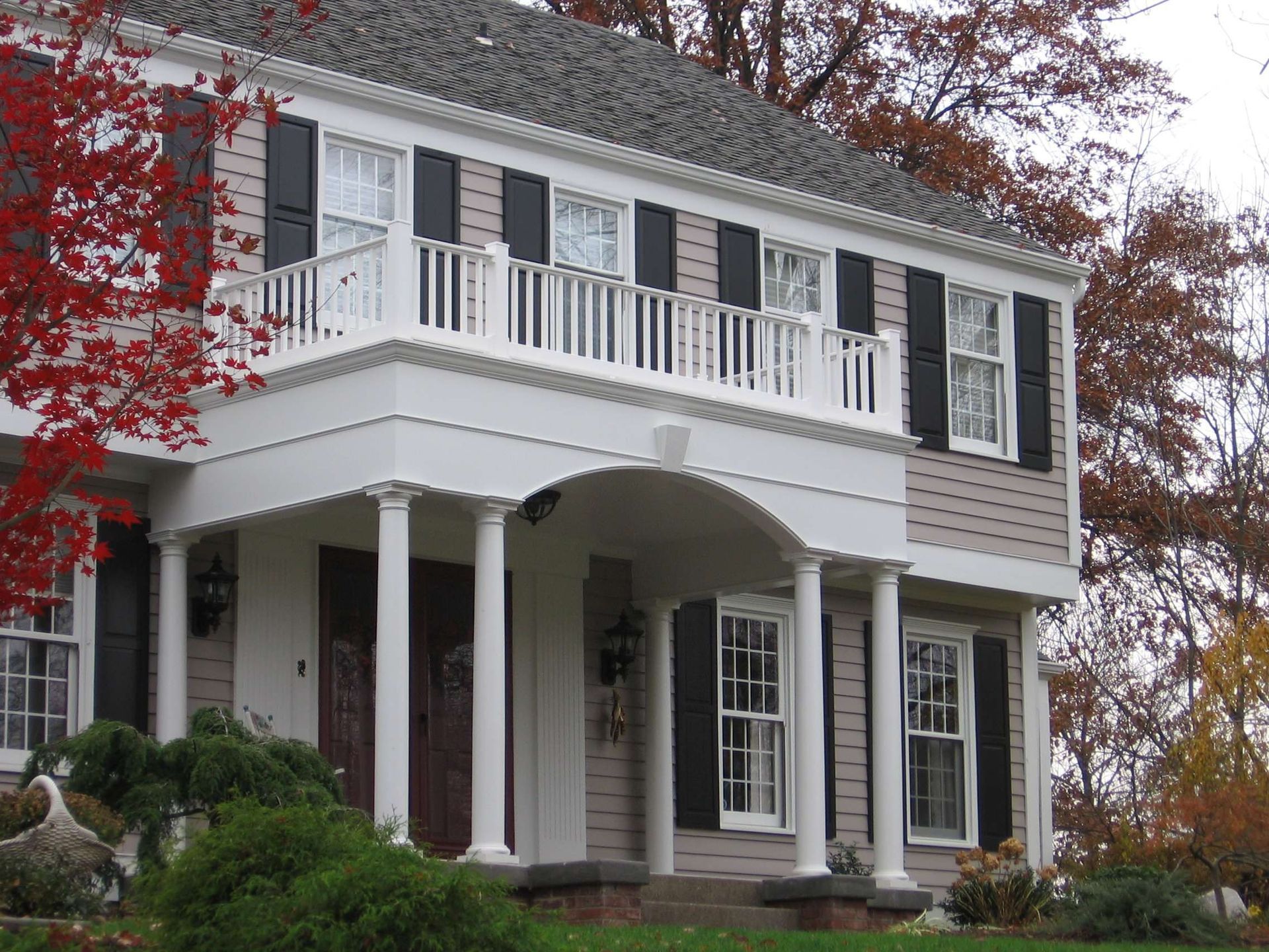 A large house with a balcony and black shutters.