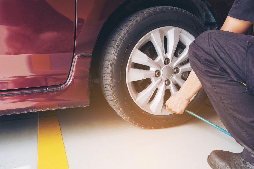 A man is changing a tire on a car in a garage.