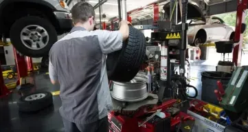 A man is changing a tire in a garage.