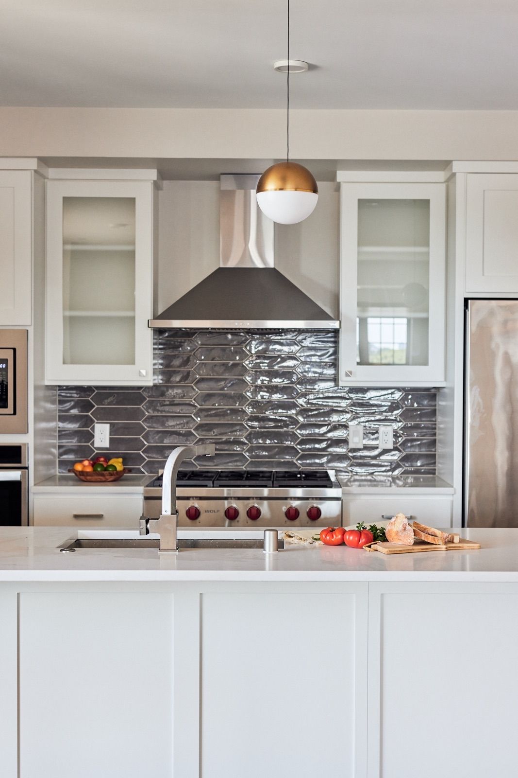 Modern kitchen with white cabinets, stainless steel appliances, and gray tile backsplash.