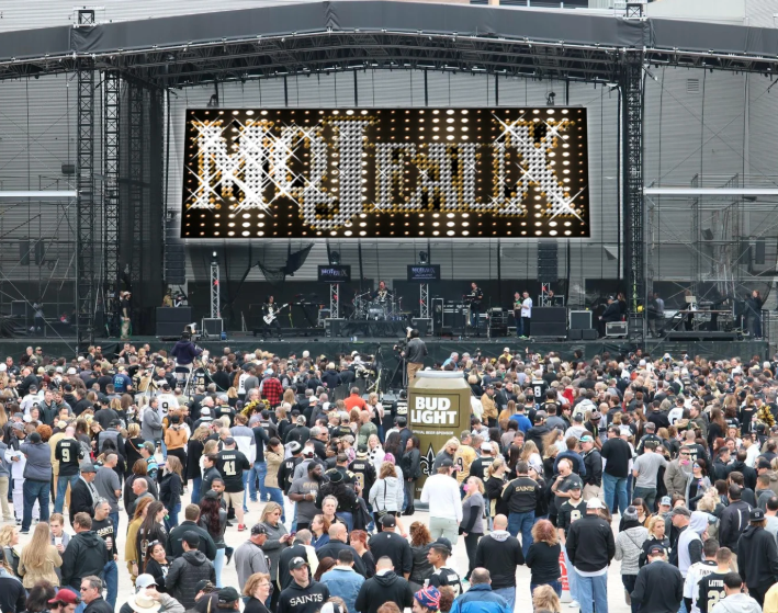 Crowd at an outdoor concert facing a large stage with a bright “MOTiMIX” sign