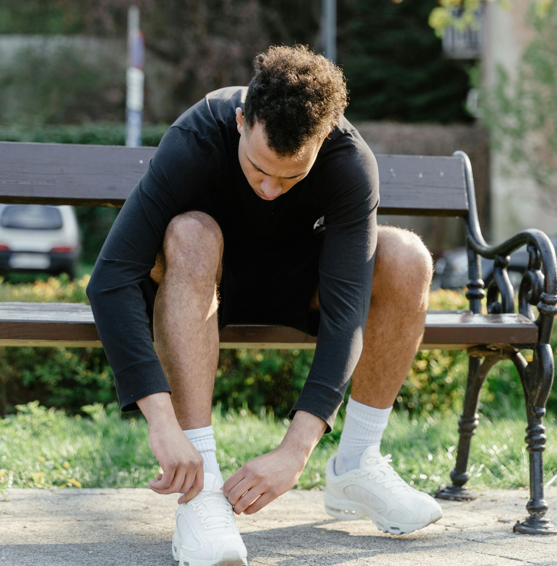 A man is sitting on a bench tying his shoes