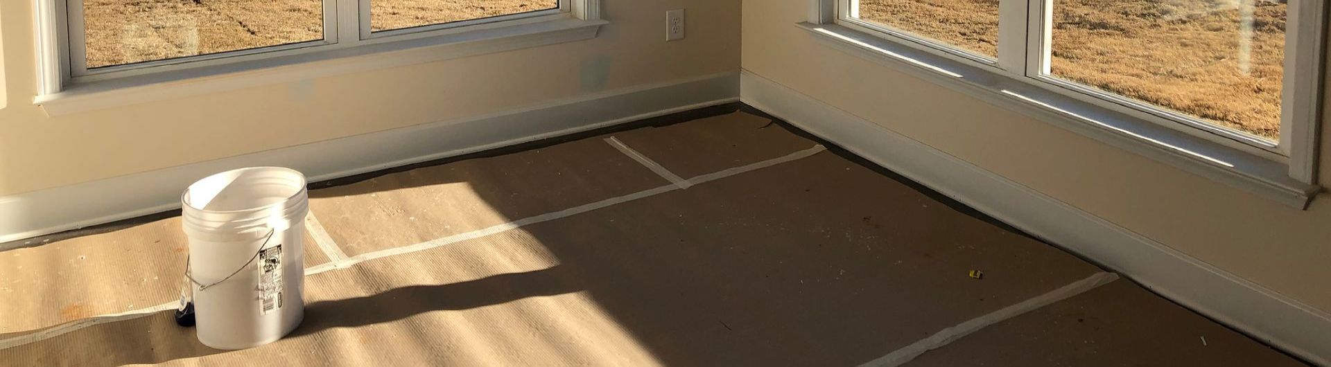 a room with two windows and a trash can on the floor