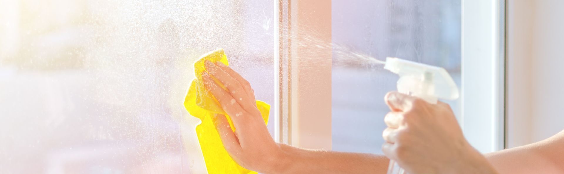 a person is cleaning a window with a spray bottle and a cloth