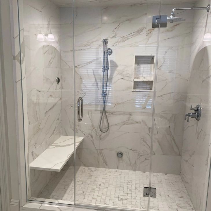 a bathroom with a walk in shower with a glass door and a bench