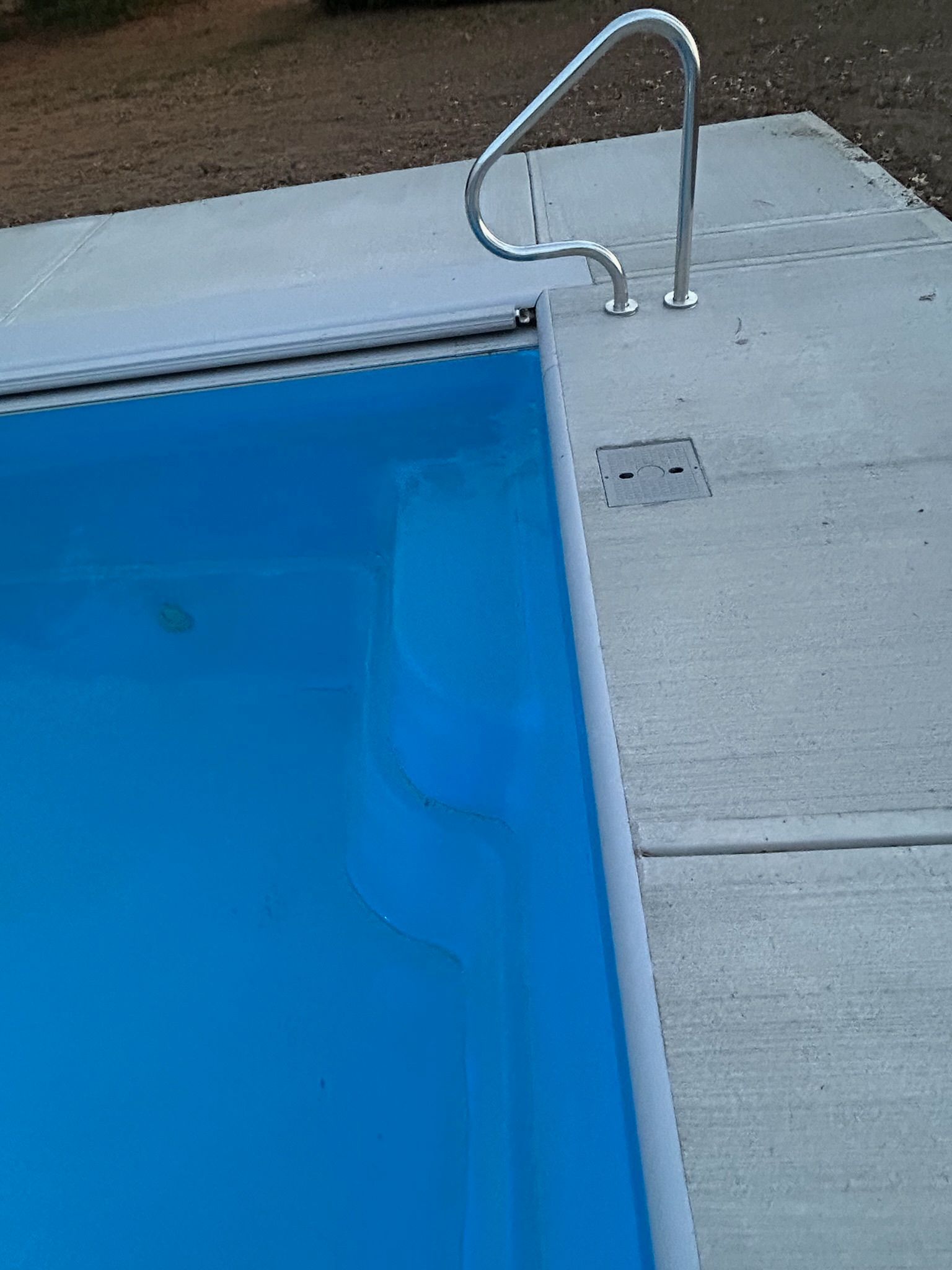 A blue swimming pool with a metal railing on the side of it