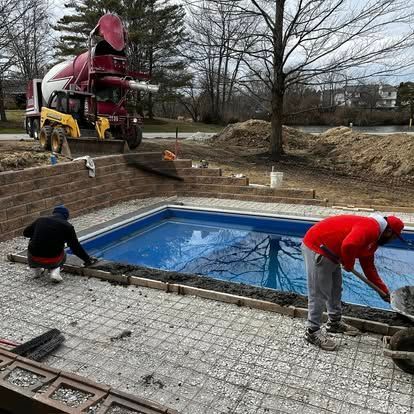 A large metal structure is sitting in front of a large red barn.
