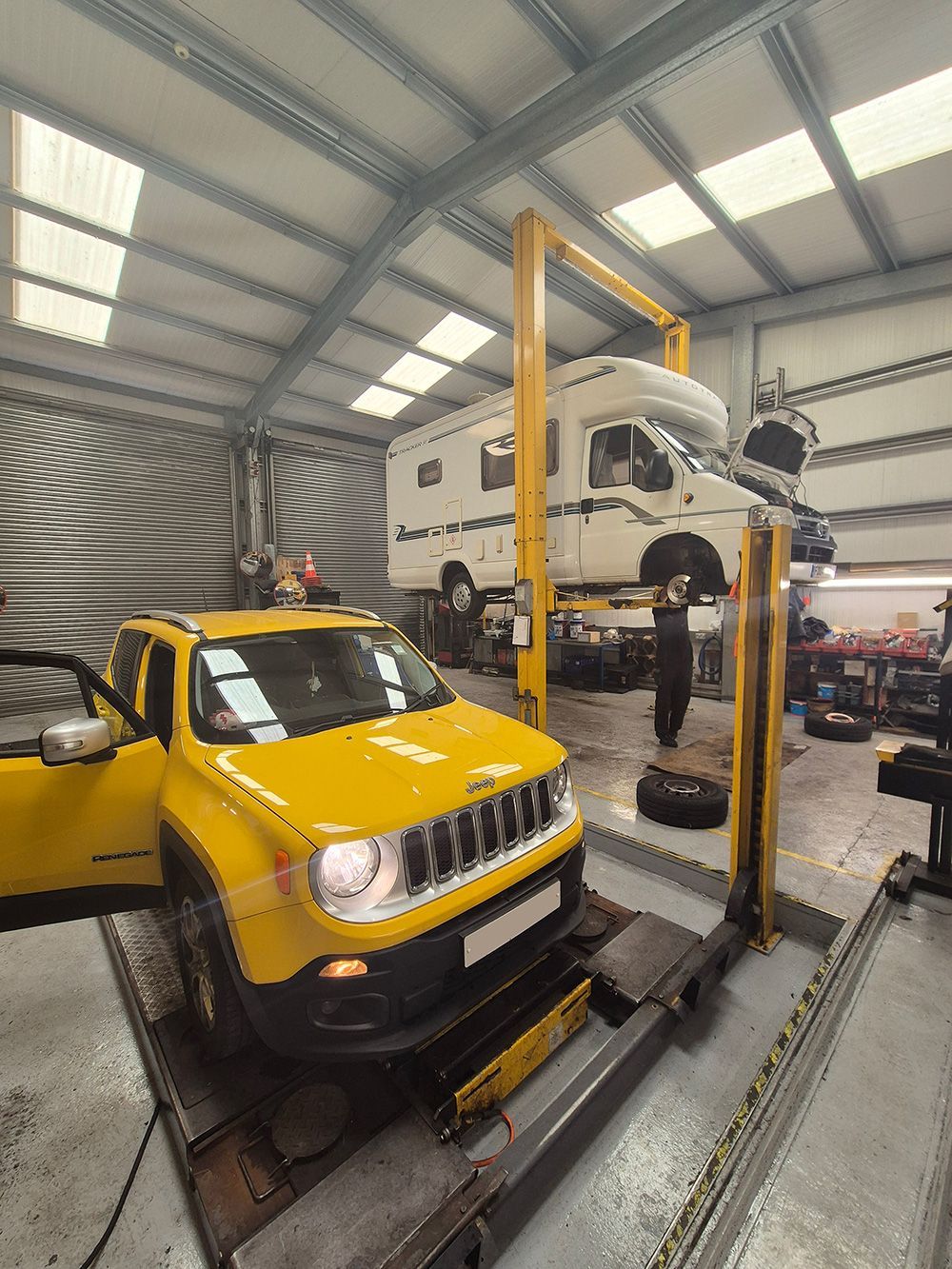 A yellow jeep is sitting on a lift in a garage.
