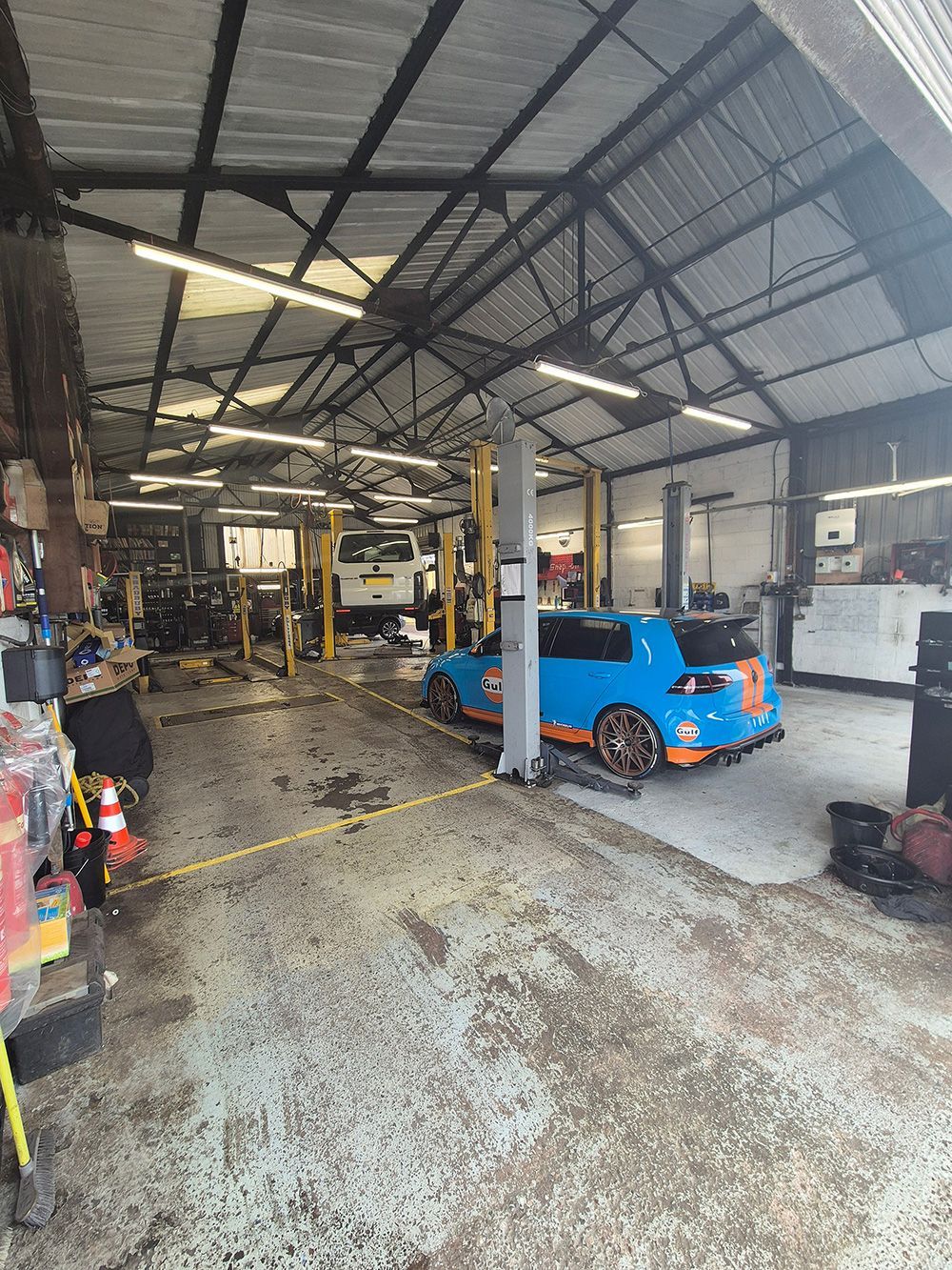 A blue car is sitting on a lift in a garage.