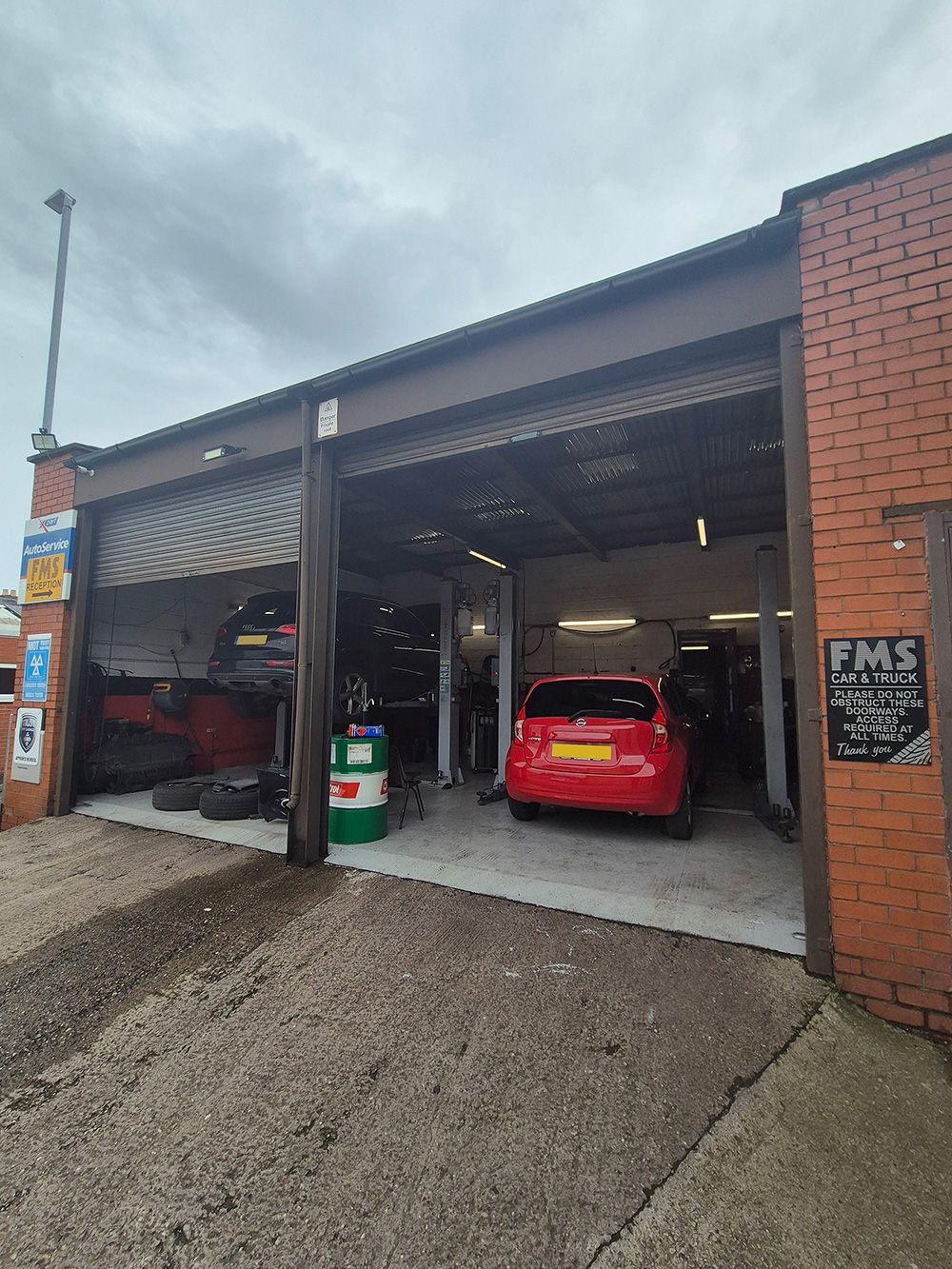 A red car is parked in front of a garage.