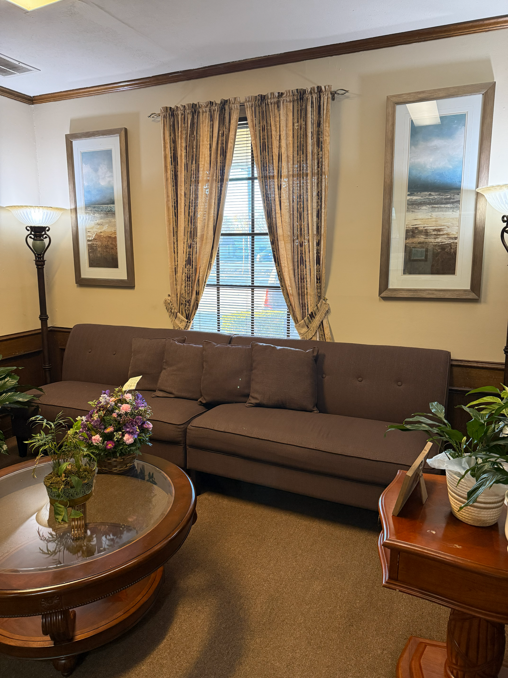The inside of a church with rows of wooden benches and stained glass windows.