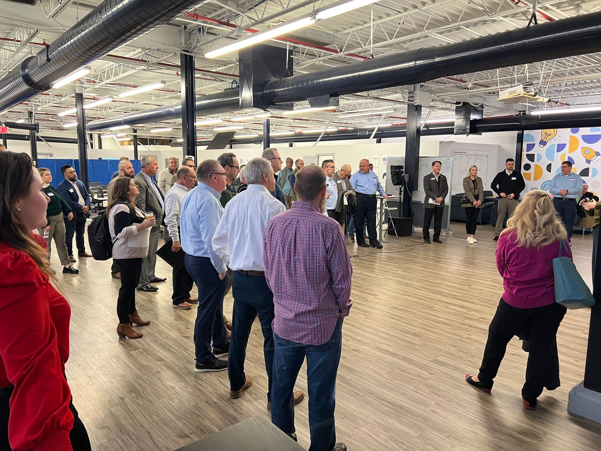 Group of people listening to a speaker in a large open space.