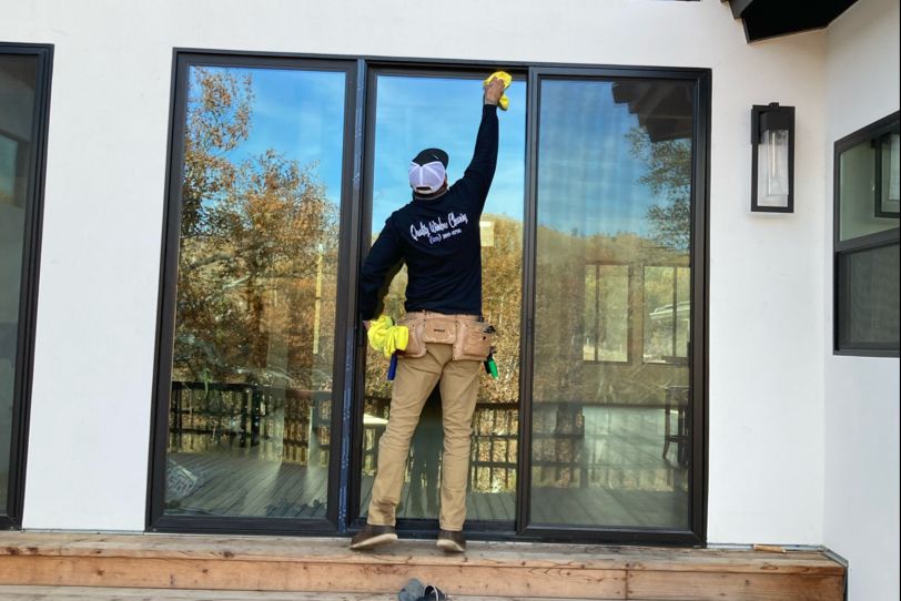 A man is cleaning a sliding glass door in a house.