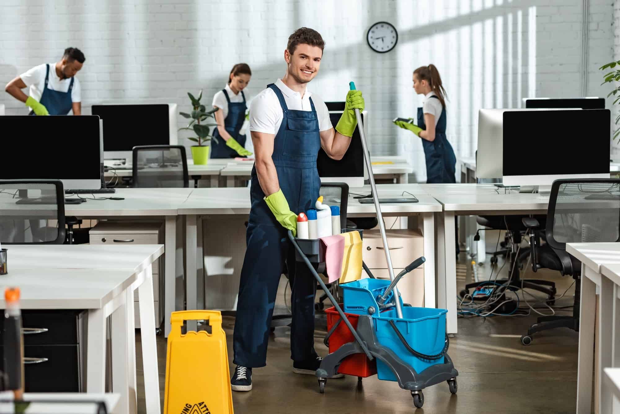 A man is cleaning an office with a mop and bucket.