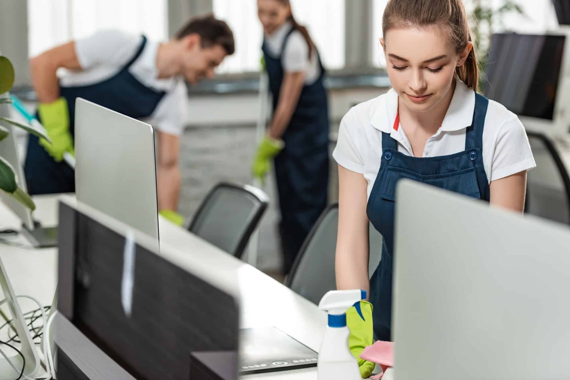 A woman is cleaning a desk in an office.