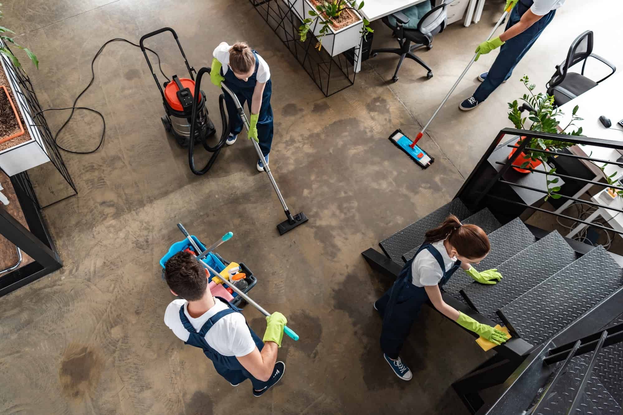 A group of janitors are cleaning an office with cleaning supplies.