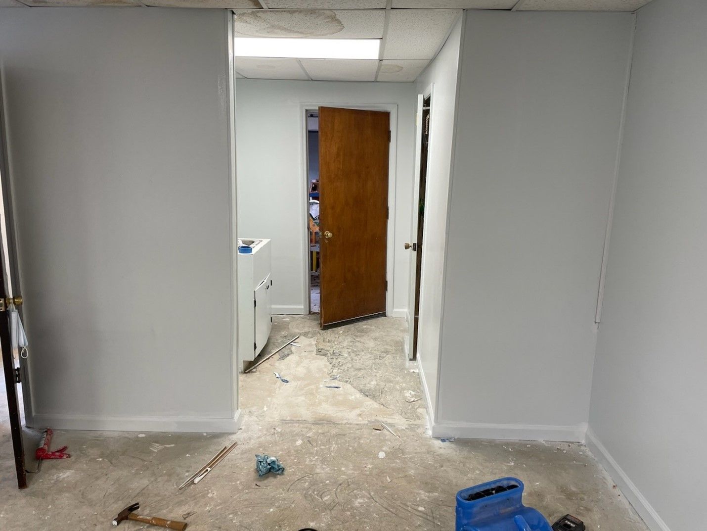 A room with a door and a hammer on the floor.