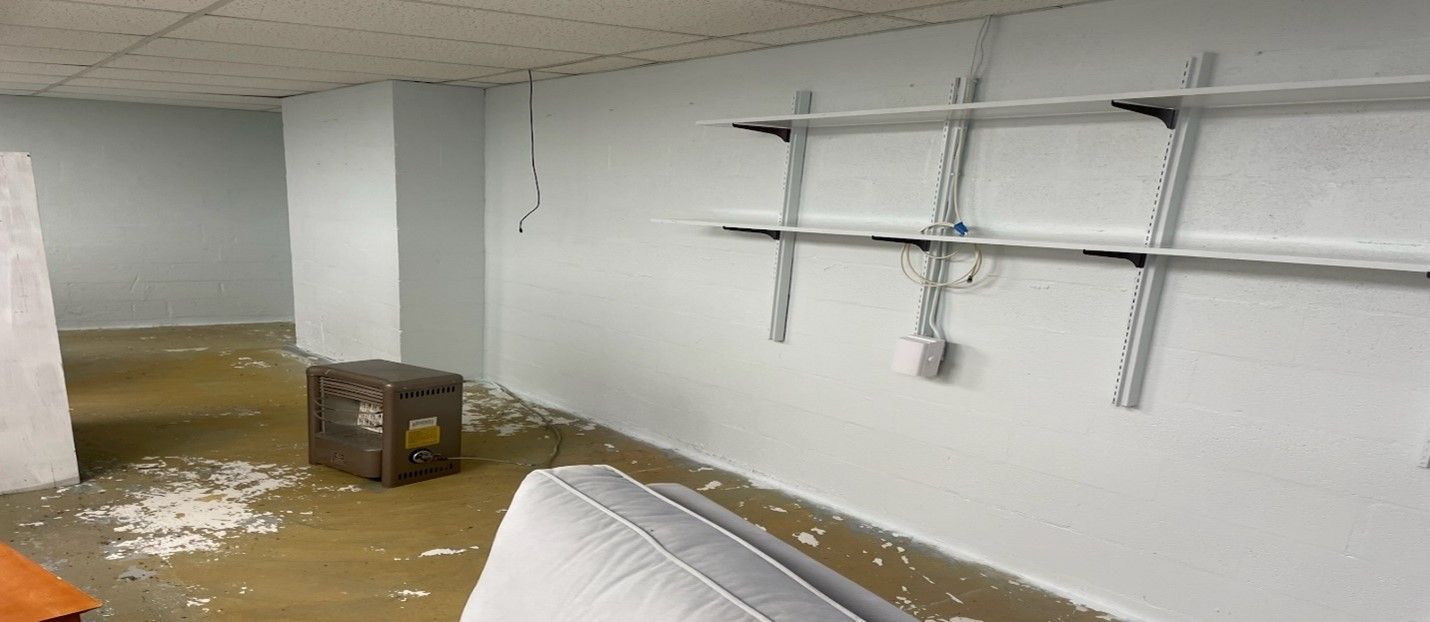 A flooded basement with a mattress and shelves.