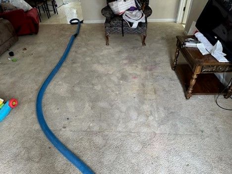 A living room with a chair , table , and vacuum hose.