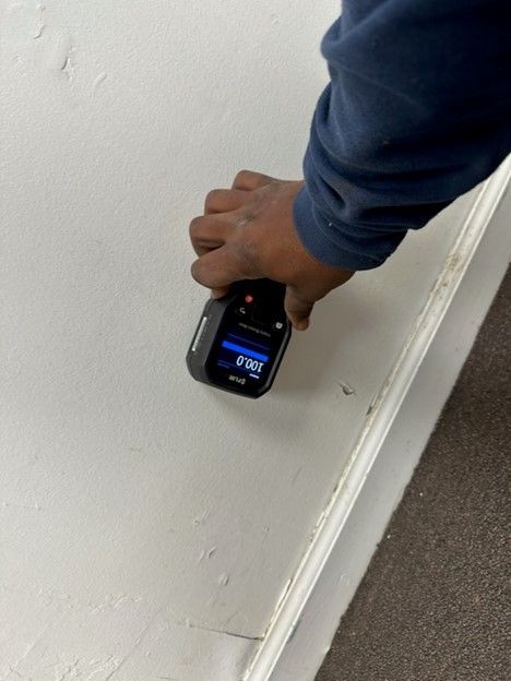 A person is measuring a wall with a device.