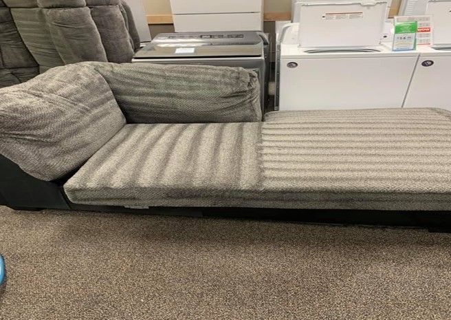 A chaise lounge is sitting on top of a carpeted floor in a room.