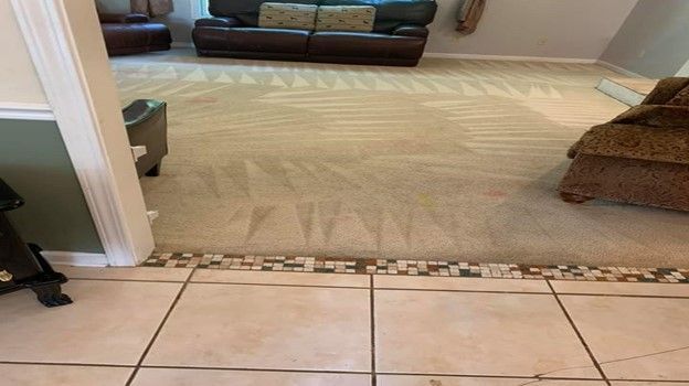 A living room with a couch and chairs and a tiled floor.