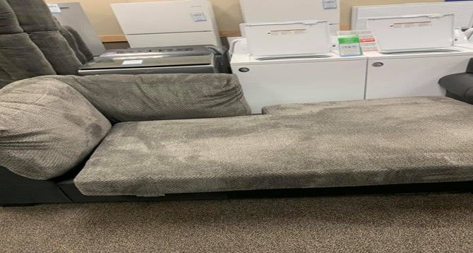 A chaise lounge is sitting on top of a carpeted floor in a room.