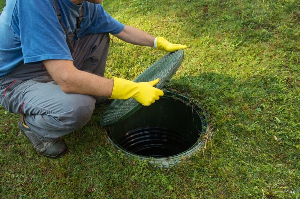 A Man Wearing Yellow Gloves is Opening a Manhole Cover — Paul Jennings in Dimbulah, QLD