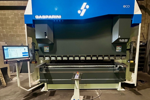 Una grande pressa piegatrice Gasparini, di colore blu e grigio, si trova in un'officina, con un monitor di controllo su un supporto.