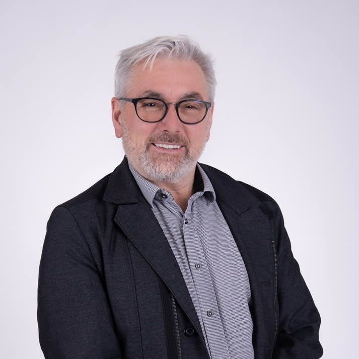 A woman with long brown hair is smiling and wearing a striped shirt
