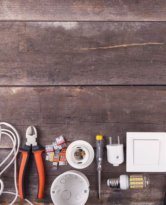 A wooden table topped with electrical equipment and tools.