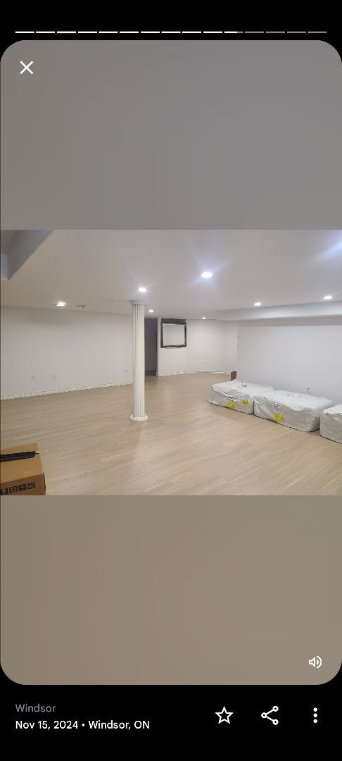 A phone screen shows a large empty room with a wooden floor.