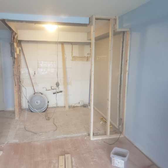 A room with a fan and a box on the floor.