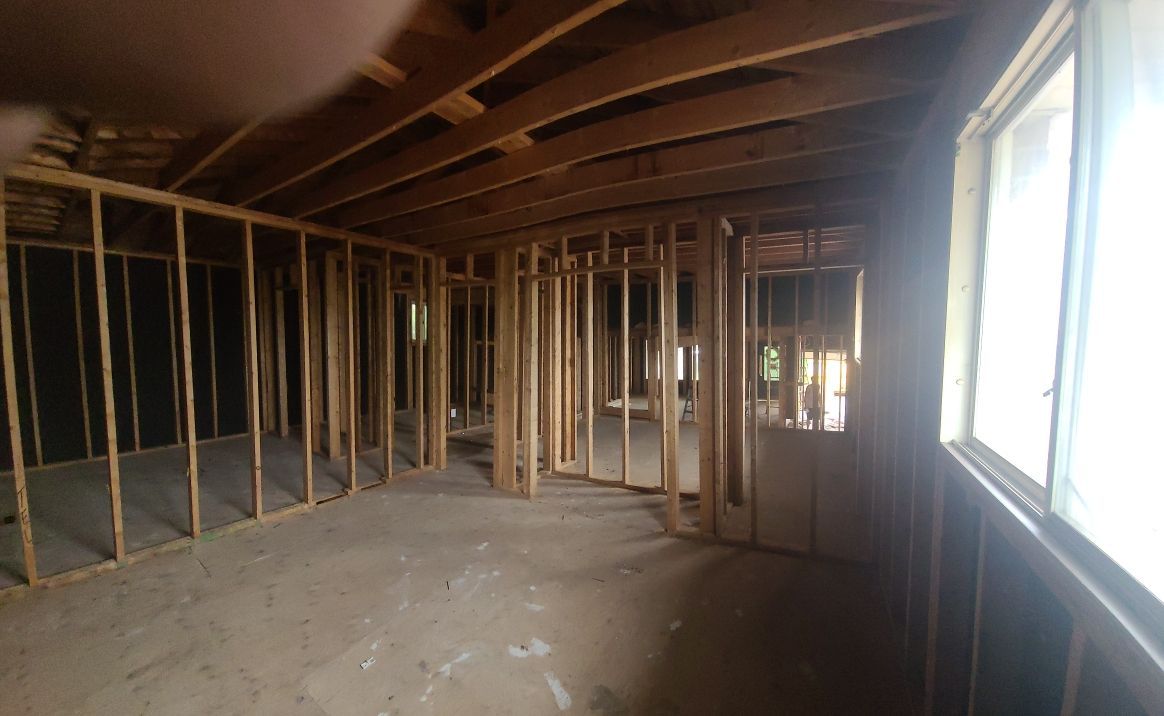 An empty room with a lot of wooden beams and windows.
