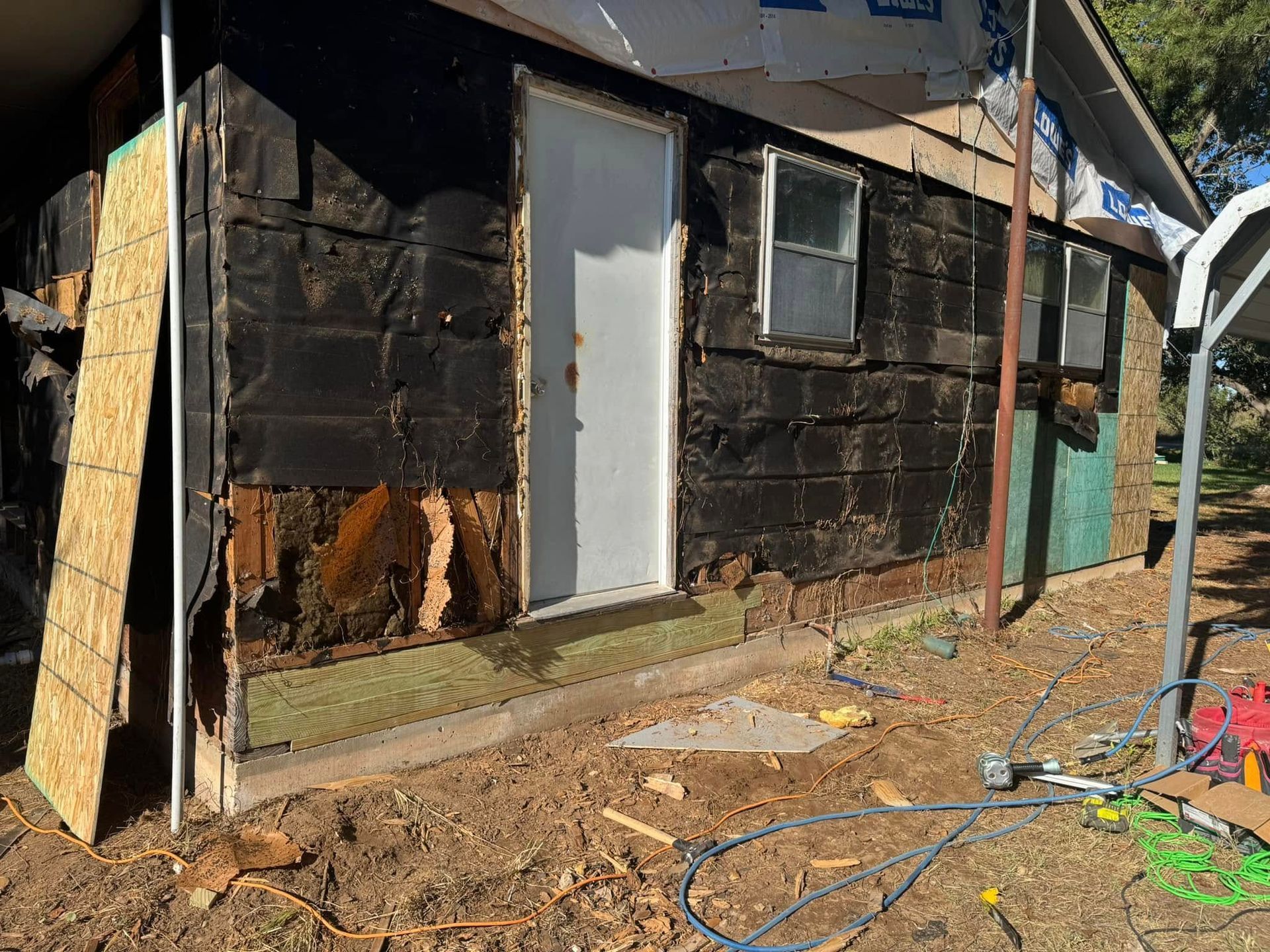 A black house with a white door is being remodeled.