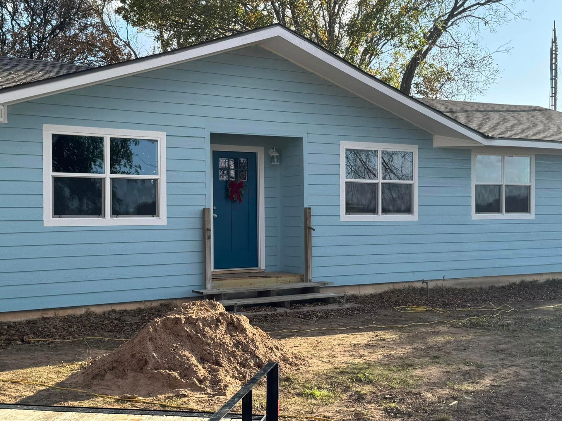 A blue house with a blue door and a pile of dirt in front of it.