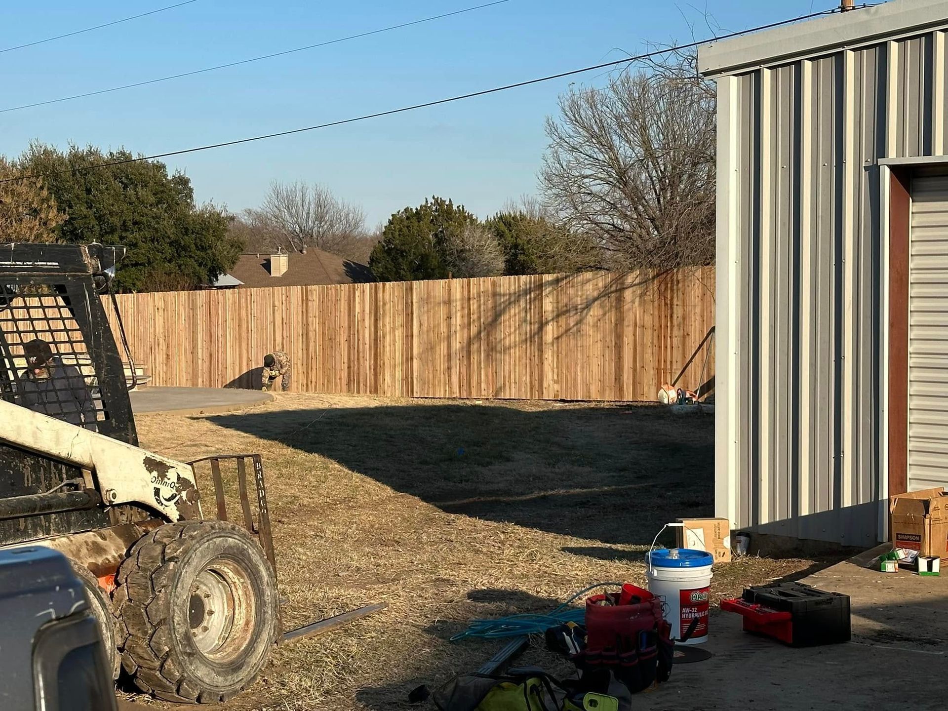 A tractor is parked in front of a wooden fence.