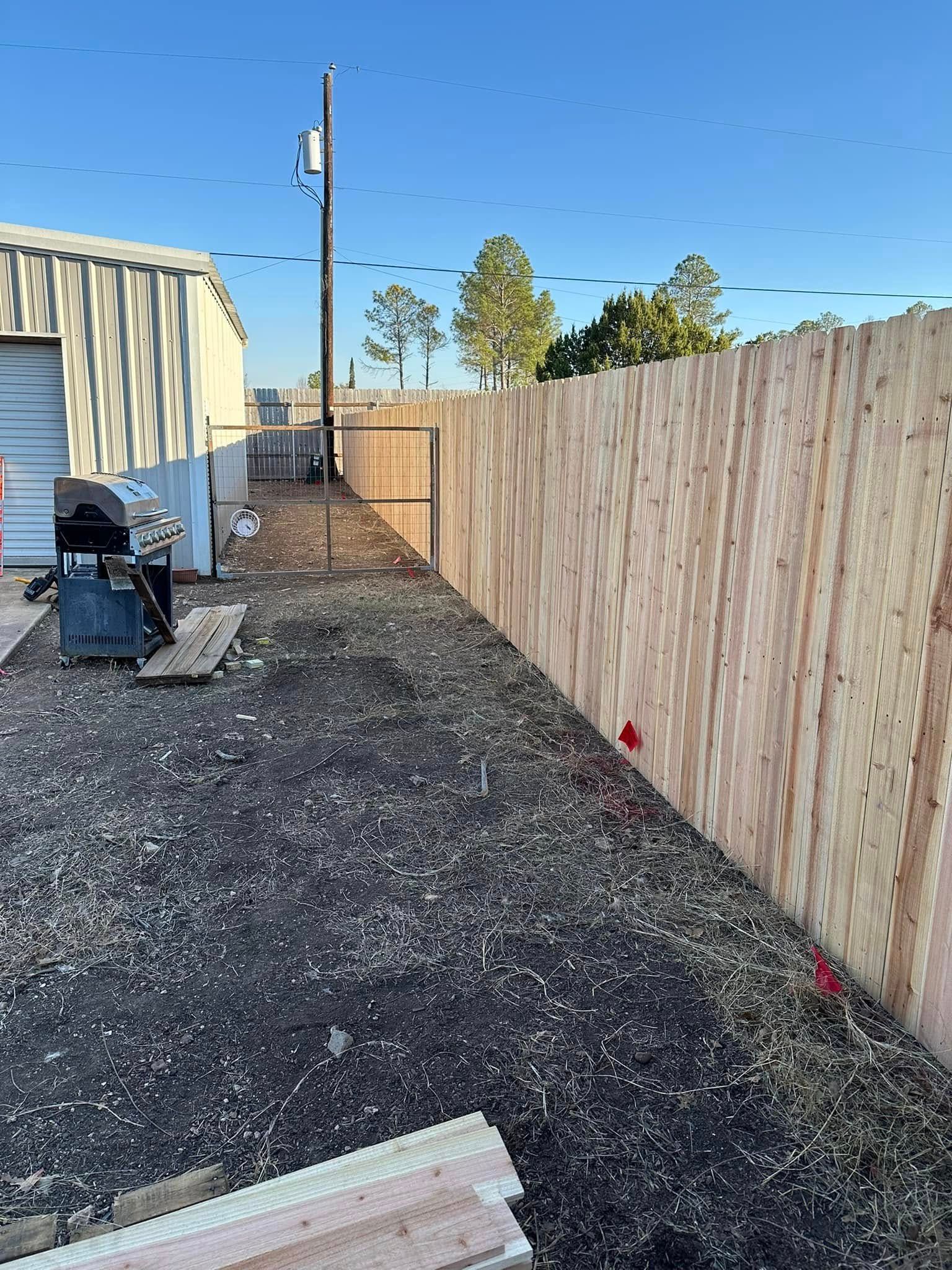A wooden fence is being built in the backyard of a house.