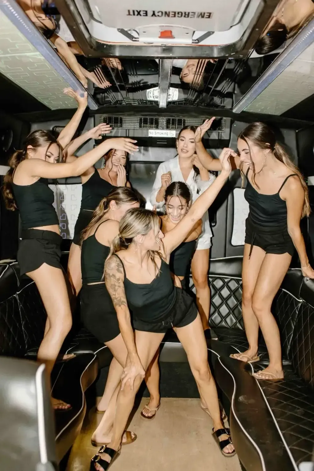 People dancing in a decorated vehicle interior, wearing black outfits, with confetti overhead
