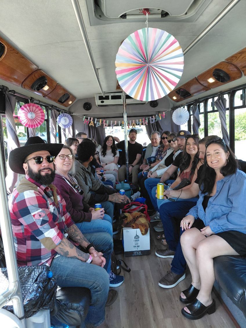Passengers seated inside a bus, chatting and smiling, with colorful circular decorations overhead.