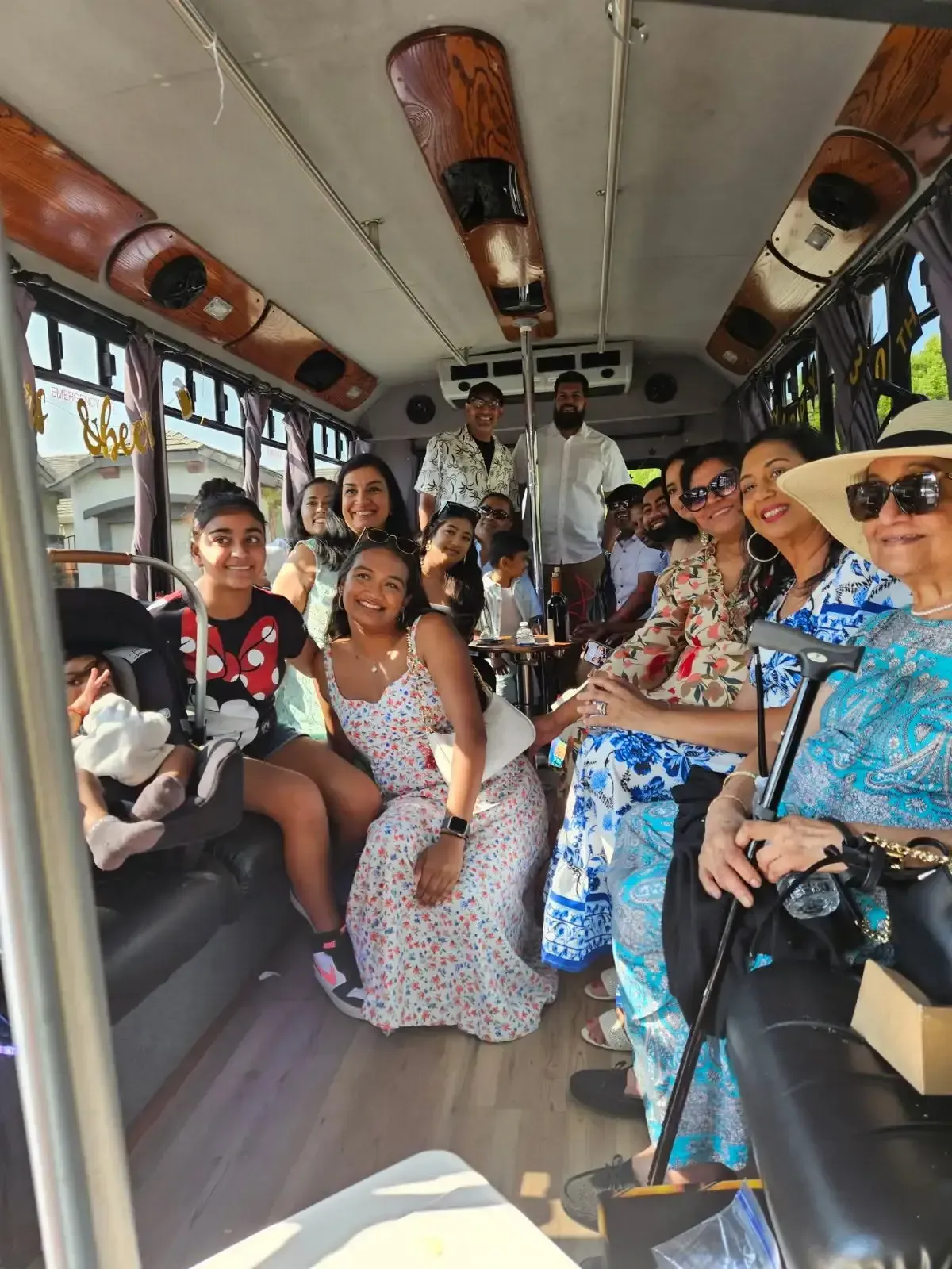 Group of people seated inside a decorated minibus, smiling and chatting during a ride