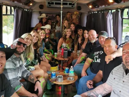 Group of people smiling and posing inside a van with curtains and a small table of drinks