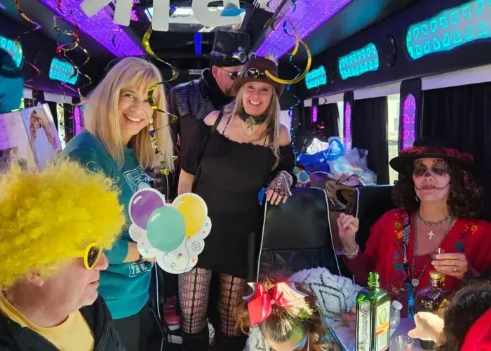 People in costumes posing inside a party bus with balloons and colorful lights