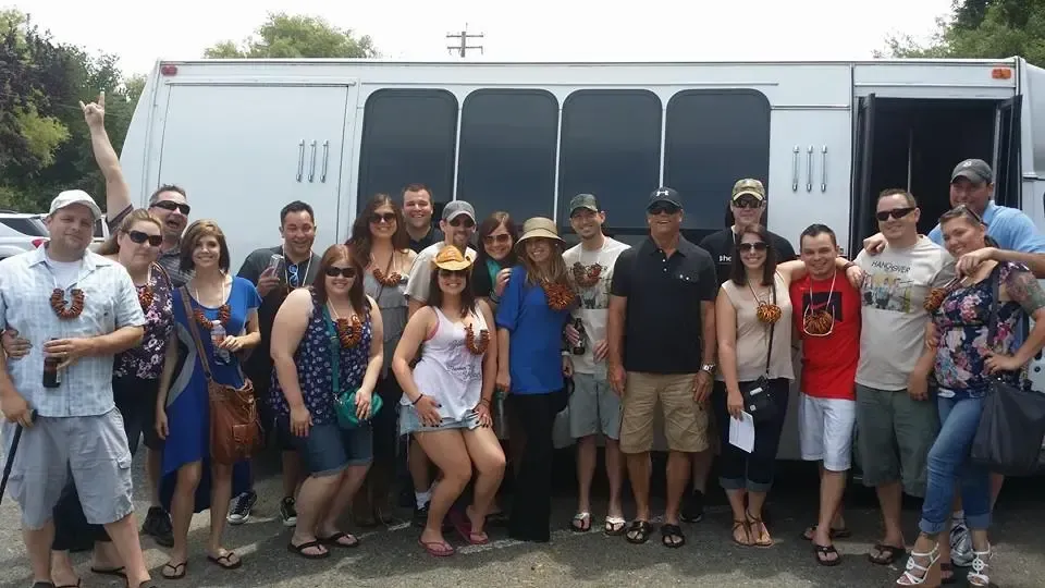 Group of people posing together in front of a white shuttle bus outdoors