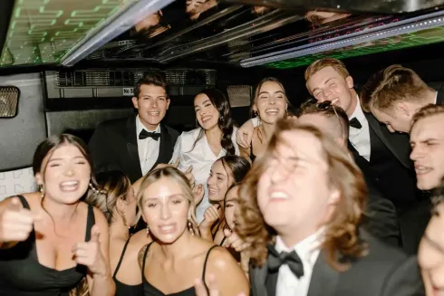 People dressed up, smiling and posing together on a party bus under colorful lights