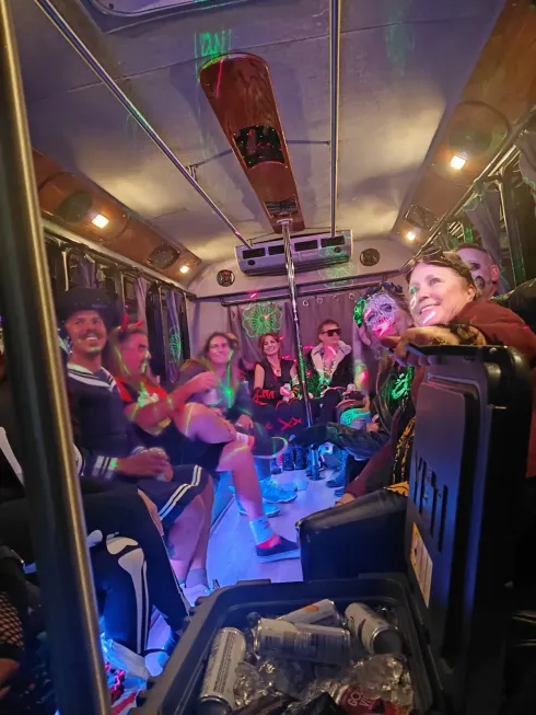 People dancing on a party bus with colorful lights and smiles.