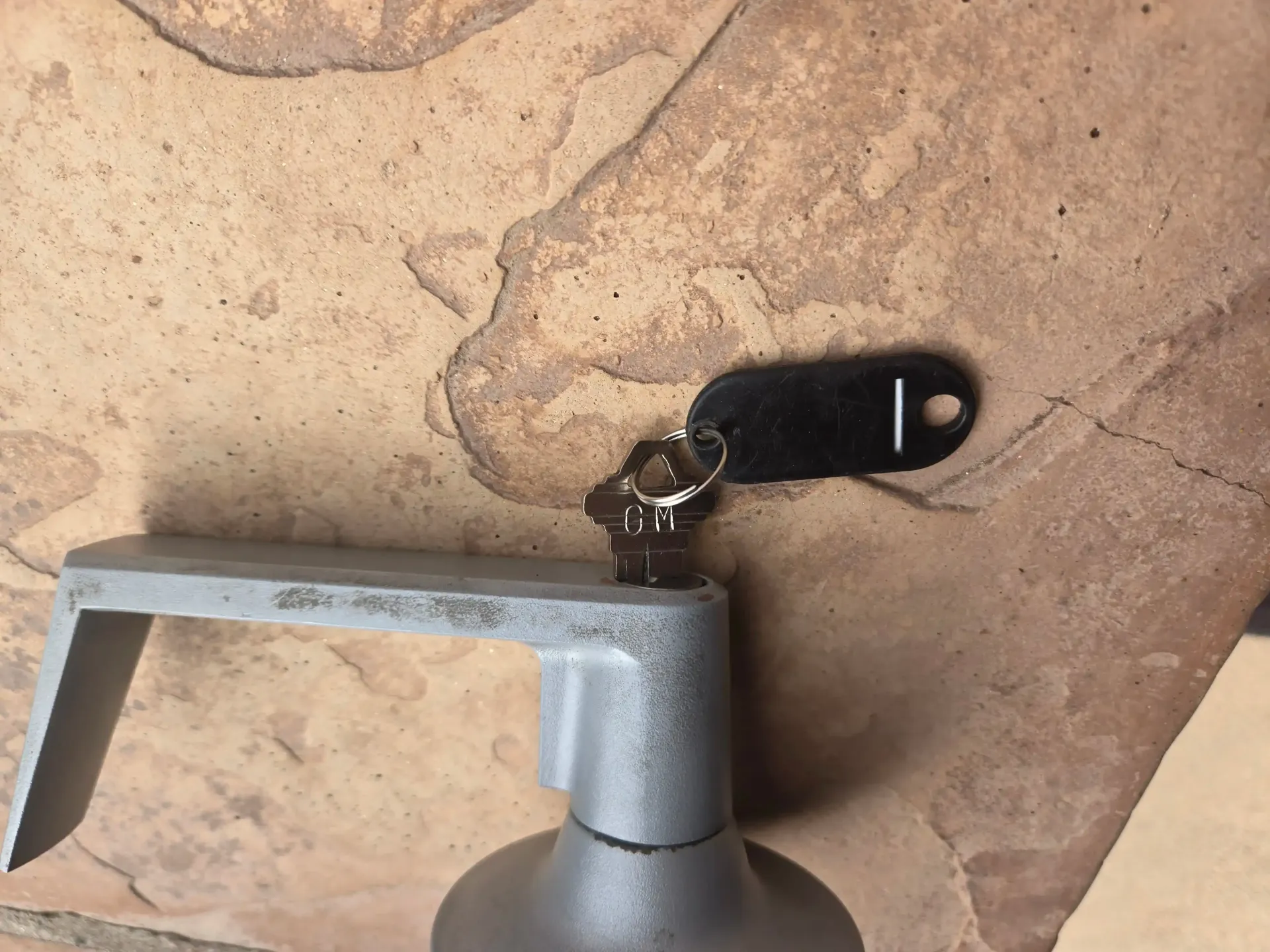 Metal faucet next to a black wall-mounted handle on a stone-textured surface